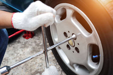 Mechanic hands change a car tyre on streetの写真素材