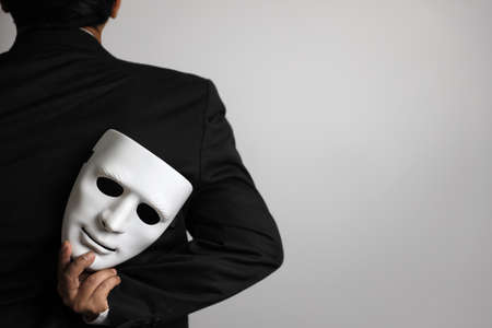 politician or businessman wearing black suit and hiding white maskの写真素材
