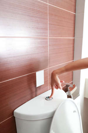 full length woman hand flush toilet after usingの写真素材