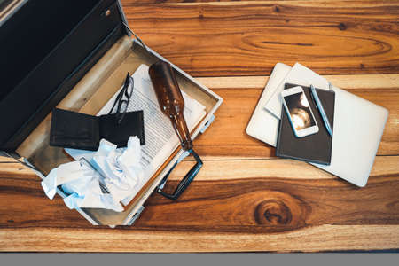 top view business bag with empty wallet, alcohol bottle and paper garbage on wood tableの写真素材