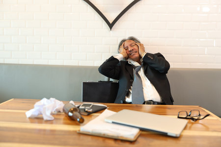 senior businessman got stress from failure in business with computer, cell phone, documents and...