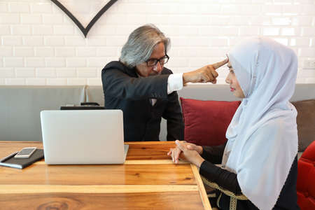 businessman muslim customer complaining muslim seller because of her work is too late with unhappy face and computer while she cryingの写真素材