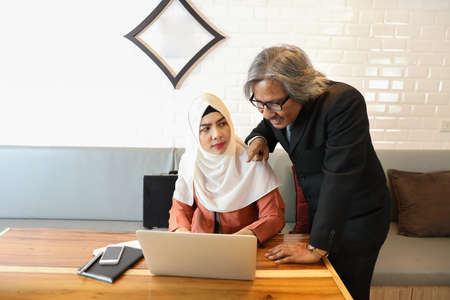 muslim customer man is harassing arab businesswoman while using computer (sexual harassment concept)の写真素材
