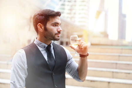 Successful caucasian business man drinking glasses of champagne with smiling while celebrating outdoorの写真素材