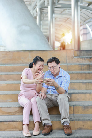 asian traveler couple husband and wife in pink and blue shirt with white nice hat sitting on the...