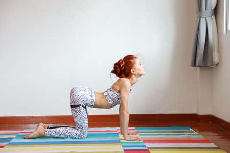 Side view of young attractive caucasian woman in black and white sportswear practicing or exercise yoga indoor. balance between body and mental. (healthy life concept)の写真素材