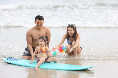 Young asian family and daughters who wearing swimwear are playing sand on the beach during happy and loving times with smiling face on holiday vacationの写真素材