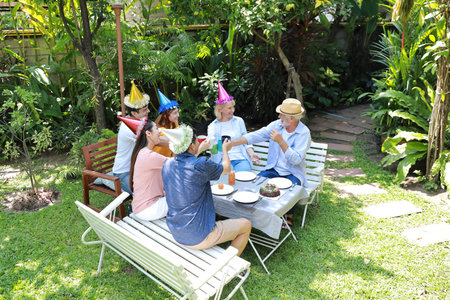 Happy multiethnic family sitting at a breakfast table in backyard outdoor on sunny day with smiling face while everyone clicking glasses.の写真素材