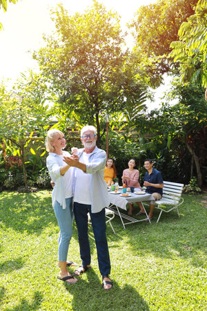 Happy multiethnic family sitting at a breakfast table in backyard outdoor on sunny day with smiling...