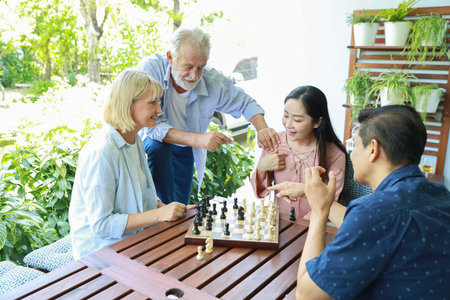 high angle view of a group of multiethnic senior people playing chess board with happy smiling face...
