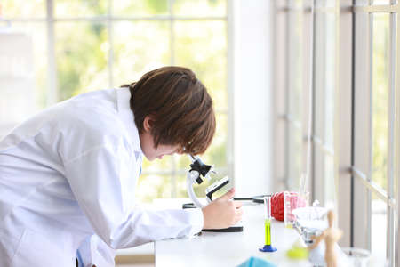 curious kid boy is experimenting science with microscope and attention face (education and scientist concept)の写真素材