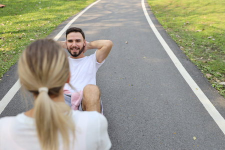 top view shot of a runner couple is jogging in the park and doing sit up with a girlfriend holding...