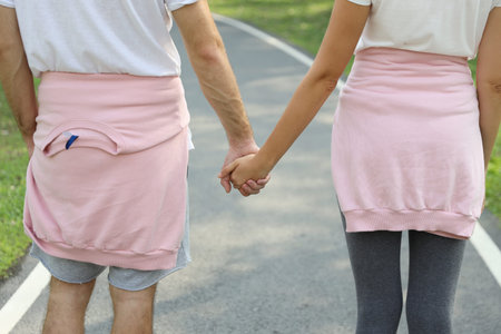 Rear view and close up young romantic couple wearing sportswear holding hands and walking together...