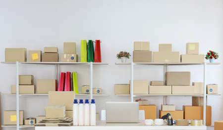 Computer on wooden working table with package product box delivery background in room in apartment indoor. Startup small business SME conceptの写真素材