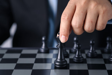 Businessman finger hands with team behind sitting and moving chess king to success position on...