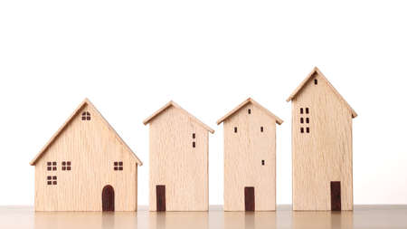 Business property investment concept, model wooden houses on wooden desk on white background studio for financial real estate advertising conceptの写真素材