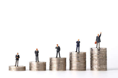 Miniature people: businessman standing stacking coins podium No.1, 2, 3, 4 and 5 isolated white background (Financial and Business competition concept)の写真素材