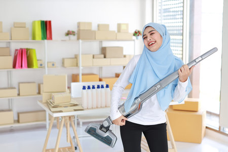 Happy young beautiful asian muslim housewife woman cleaning and playing vacuum cleaning like guitar...