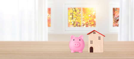 Business property investment model wooden house with piggy bank on bright interior room background with copy space, financial real estate advertising conceptの写真素材