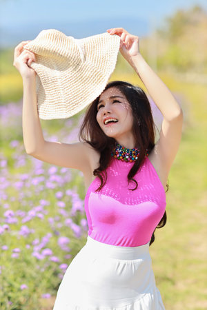 Asian beautiful woman, long hair in cute dress and hat on Verbena filed in winter with blue sky....