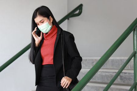 Young asian business woman in business black suit with protect mask for healthcare walking on...