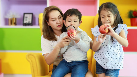 Happy asian family mother, child daughter and son sitting on sofa in colorful modern living room...