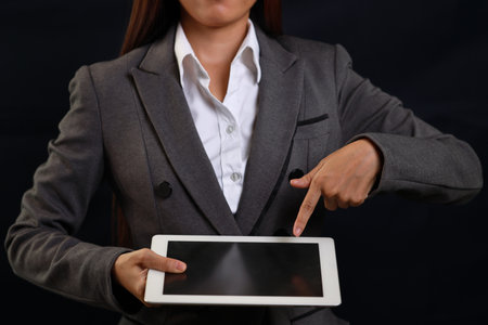 Attractive professional female hands standing and showing blank screen on tablet  for advertising on black background isolatedの写真素材