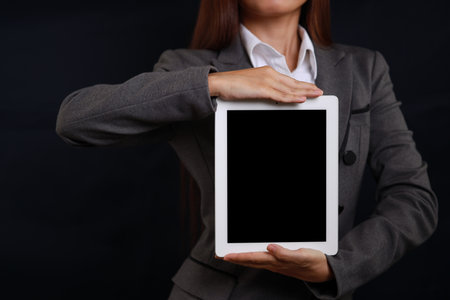 Attractive professional female hands standing and showing blank screen on tablet  for advertising on black background isolatedの写真素材