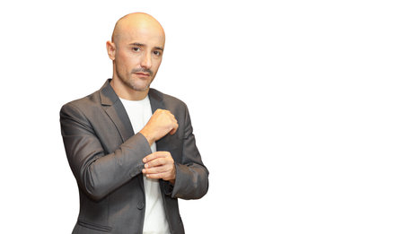 Unhappy face of middle aged caucasian man find himself get bald or lost hair in grey suit on white...
