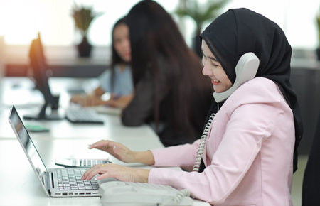 Attractive professional asian muslim female employee worker sitting, using laptop computer and...