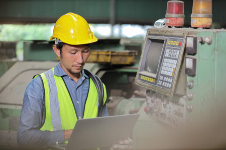 Technician engineer or worker in protective uniform standing and using computer while controlling...