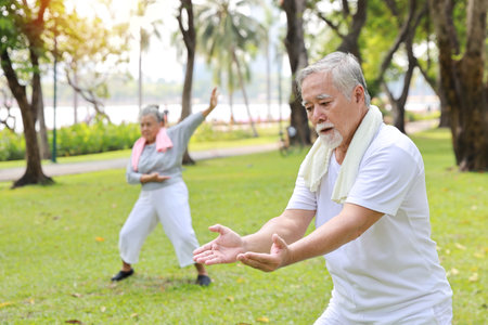 Asian senior couple practice yoga excercise, tai chi tranining, stretching and meditation together with relaxation for healthy in park outdoor after retirement. Happy elderly outdoor lifestyle conceptの写真素材