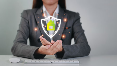 Attractive professional female hands show protecting house futuristic graphic shield with laptop computer keyboard. Businesswoman sitting with white background. Property insurance and security conceptの写真素材