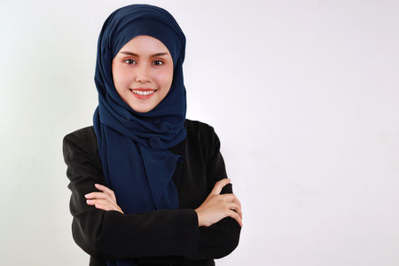 Happy and smart asian business woman in muslim dress standing and arms cross with confident in studio. Isolated white background portrait with beautiful face in hijab. Advertisement portrait conceptの写真素材