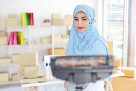 Active young beautiful asian housewife woman cleaning with vacuum cleaning floor after working SME with E-commerce Package box background. Cleaning girl in muslim black leggings vacuuming her room.の写真素材