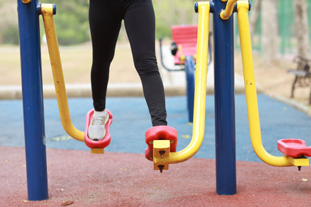 Close up healthy young asian woman in sportswear relaxing on public exercise machine outdoor.の写真素材