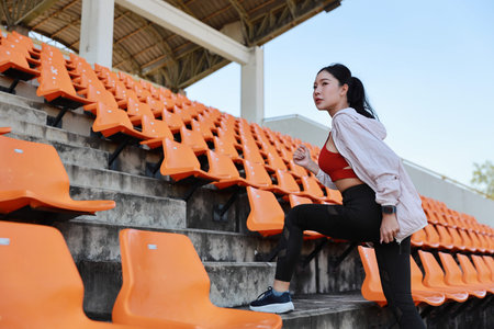Side view strong and beautiful asian fitness female sportswoman morning run and workout at stadium