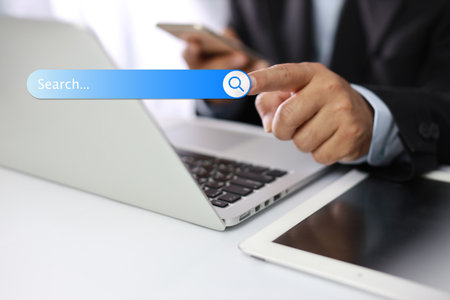 Smart male hands using laptop computer keyboard and smartphone searching, browsing internet data online information with search bar console interactive on screen. Lifestyle with technologyの写真素材