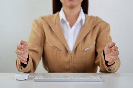 Attractive professional female hands in classic suit show protecting something on keyboard. Businesswoman sitting on table with black background. Property insurance and security conceptの写真素材