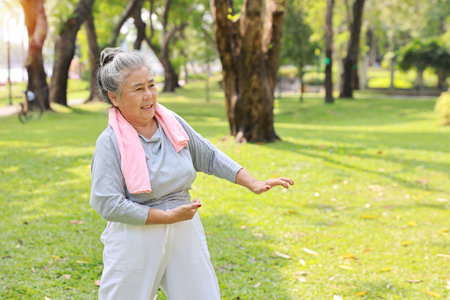 Asian senior woman practice yoga excercise, tai chi tranining, stretching and meditation together with relaxation for healthy in park outdoor after retirement. Happy elderly outdoor lifestyle conceptの写真素材