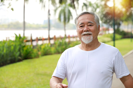 Happy and smiling asian senior man doing exercise and jogging or walking with relaxation for healthy in park outdoor after retirement during summer time. Health care elderly outdoor lifestyle concept.の写真素材