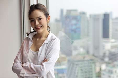 Portrait of confident and beauty young asian businesswoman with happy smiling face standing and looking at camera in modern hotel with city blurred background. Success business and lifestyle conceptの写真素材