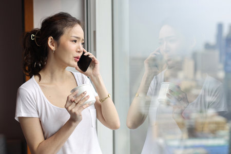 Portrait of confident and beauty young asian businesswoman with coffee cup standing and looking away in modern hotel with city blurred background. Success business and lifestyle conceptの写真素材