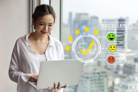 Happy customer asian woman pressing on online application screen with excellent 5.0 rating for service evaluation on computer virtual touch screen. Customer satisfaction survey experience concept.の写真素材