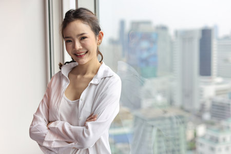 Portrait of confident and beauty young asian businesswoman with happy smiling face standing and looking at camera in modern hotel with city blurred background. Success business and lifestyle conceptの写真素材