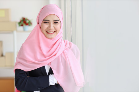 Religious asian woman in blue muslim suit and pink shaft on head standing and looking at camera with confidence. Business woman stand with package SME box delivery background. Work at home conceptの写真素材