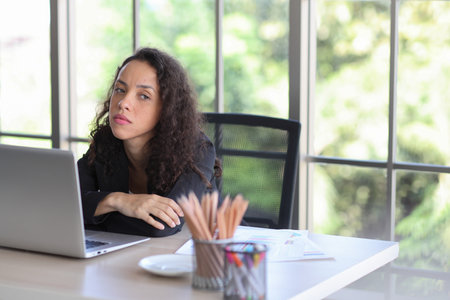 Mid adult businesswoman touching got headache while looking away in office after bad news business failure or get fired and feeling discouraged, distraught and hopeless in modern office.の写真素材