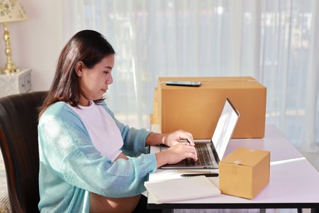 Attractive happy asian pregnant woman sitting and using mobile smart phone and checking order for customer with tablet. Expectant mother preparing and working for baby birth during pregnancy concept.の写真素材