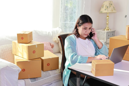 Attractive happy asian pregnant woman sitting and using mobile smart phone and writing order for customer with tablet. Expectant mother preparing and working for baby birth during pregnancy concept.の写真素材