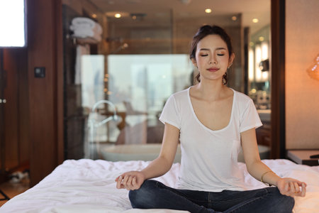 Asian woman wearing white sleepwear practicing mediate yoga. Lifestyle concept.の写真素材
